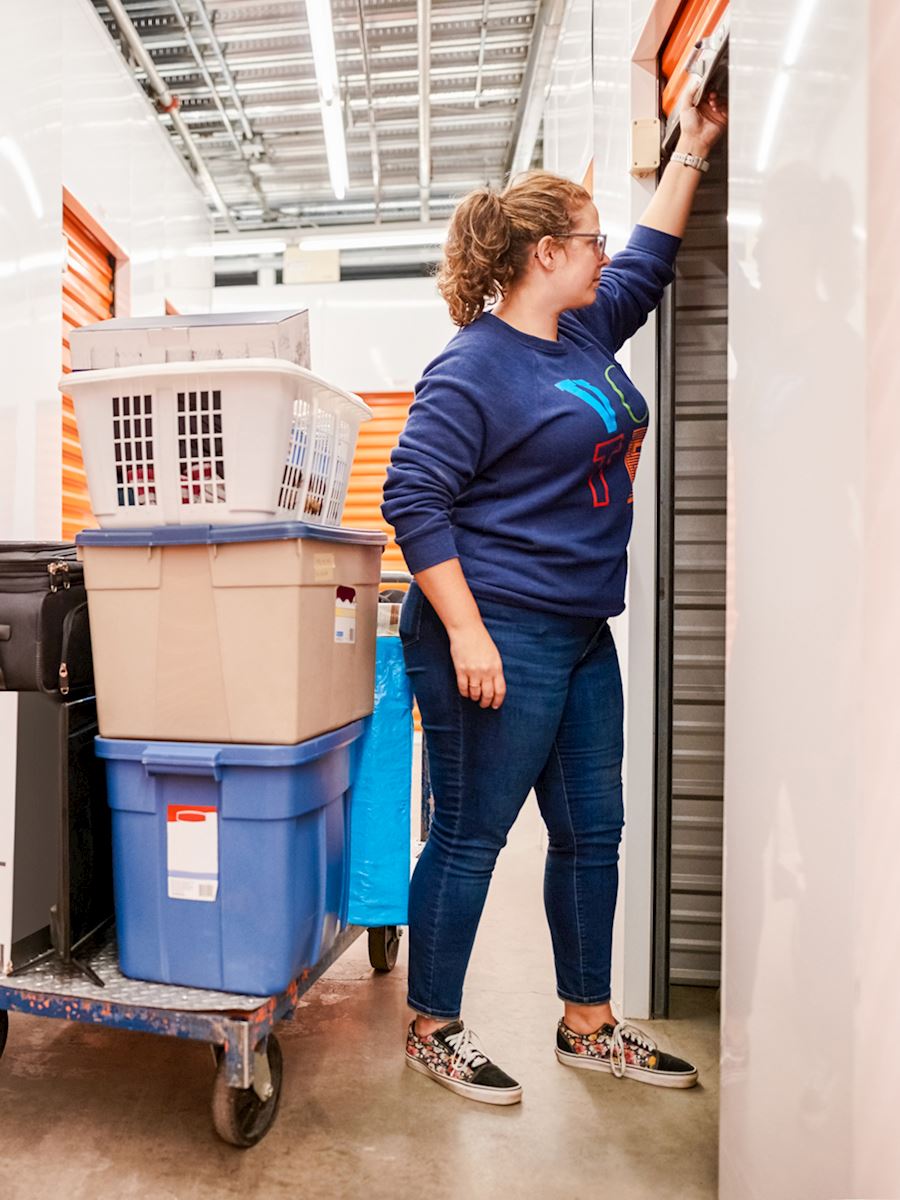 Woman opening a storage unit beside a cart of bins